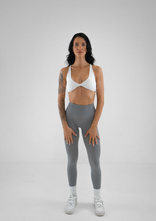 Model wearing grey activewear leggings and white bra set 