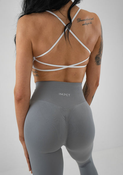 Model wearing a white activewear bra and grey leggings set 