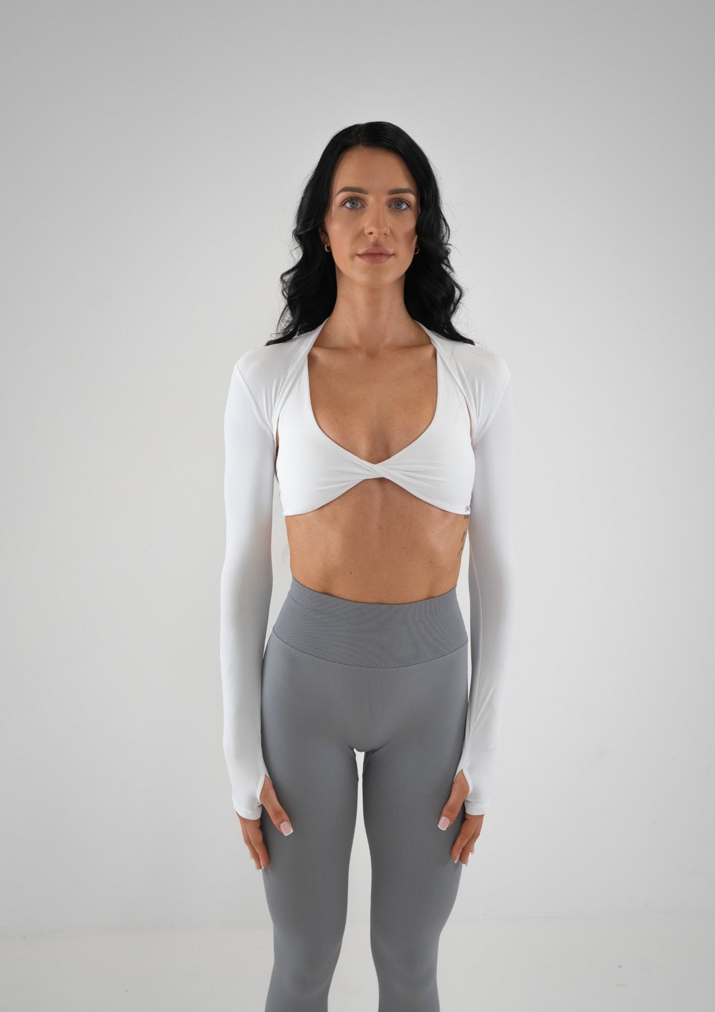 Model wearing a white activewear bolero and grey leggings