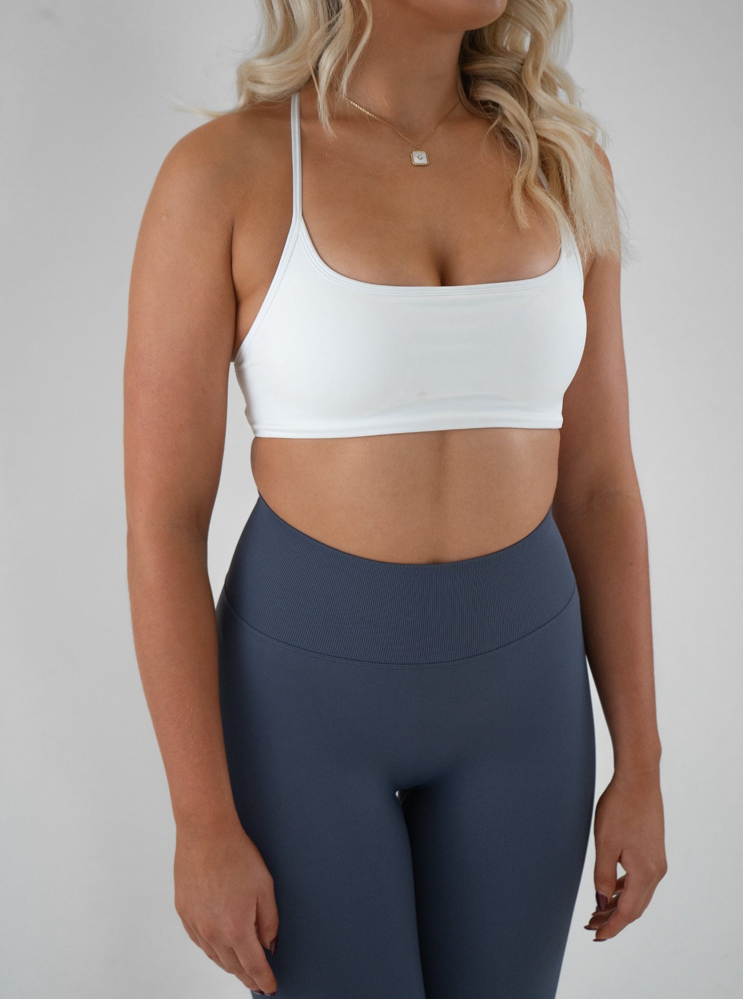 Model wearing blue colour activewear leggings and white bra set 