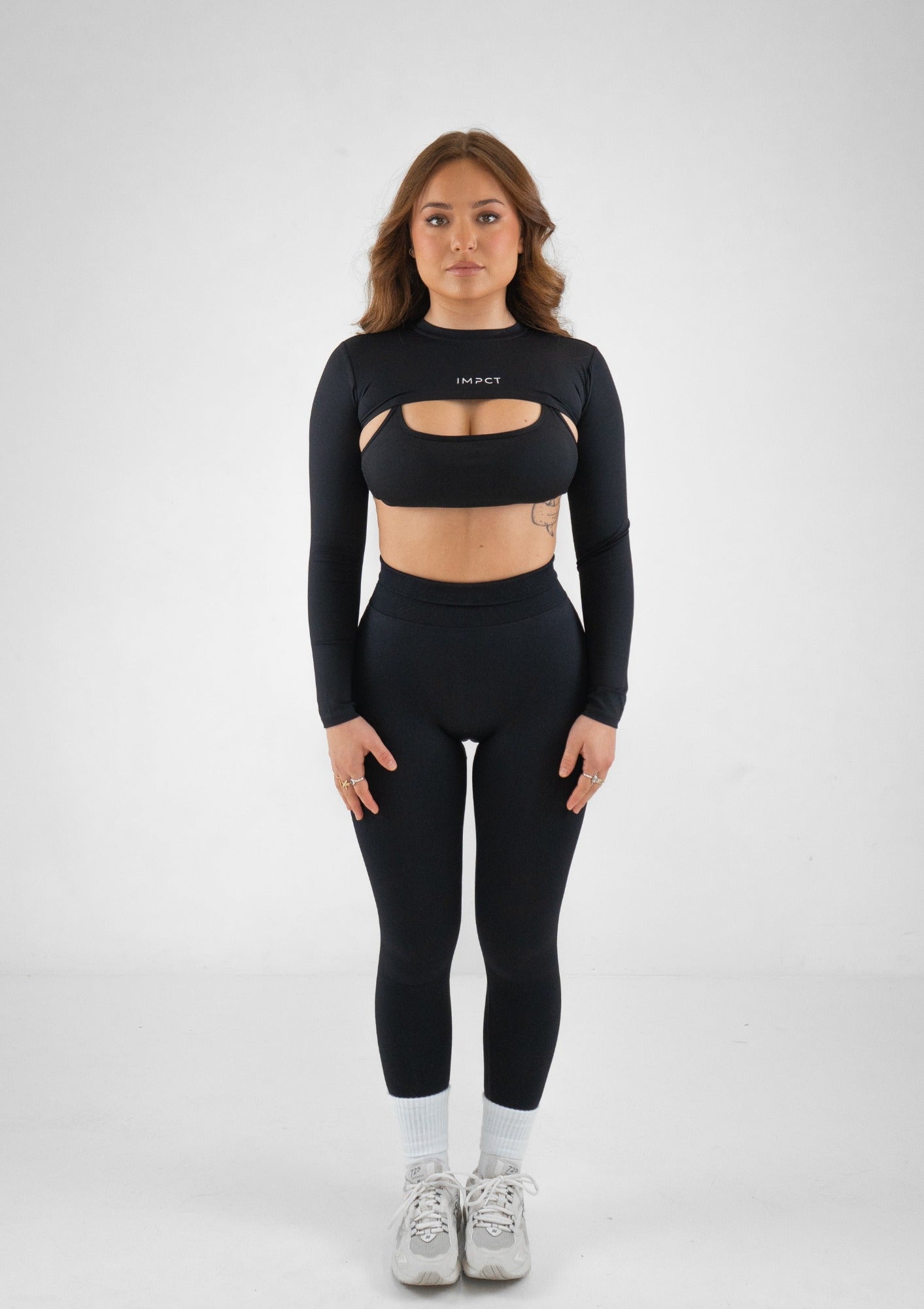 Model wearing a black activewear set with a black shrug