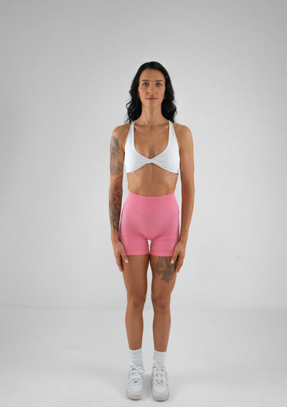 Model wearing pink activewear shorts and white bra set