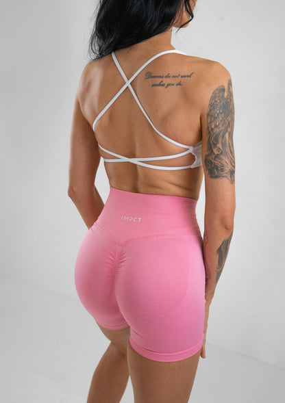 Model wearing pink activewear shorts and white bra set