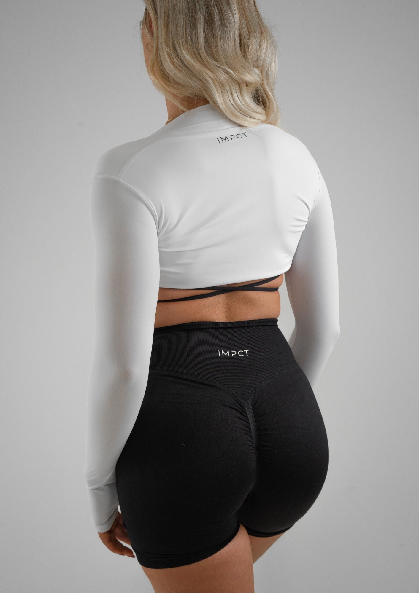 Model wearing black activewear shorts and bra set with white bolero