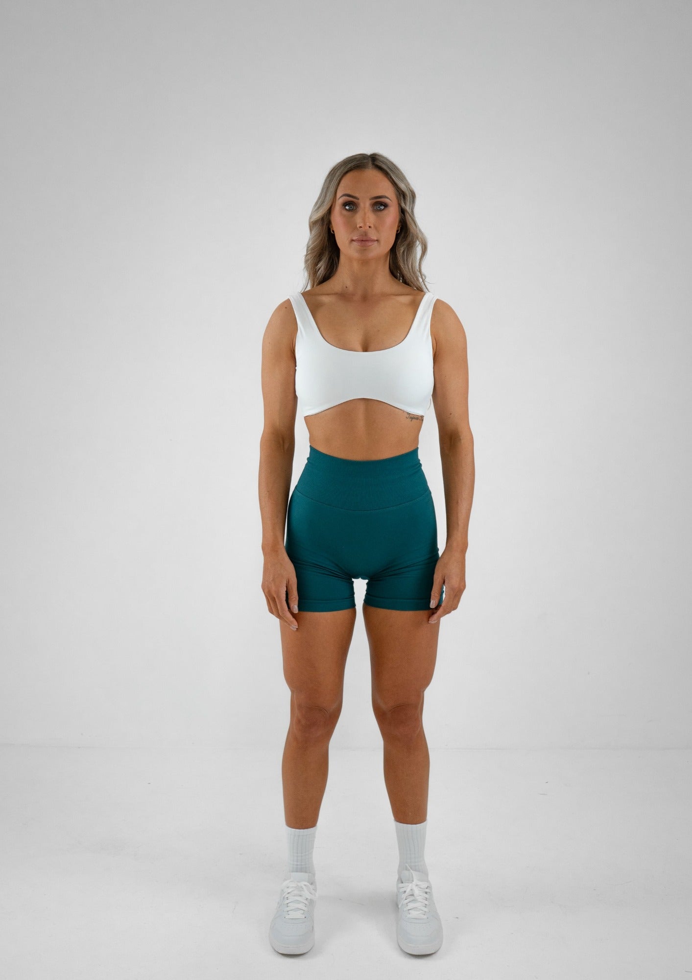 Model wearing a white activewear bra and green shorts set