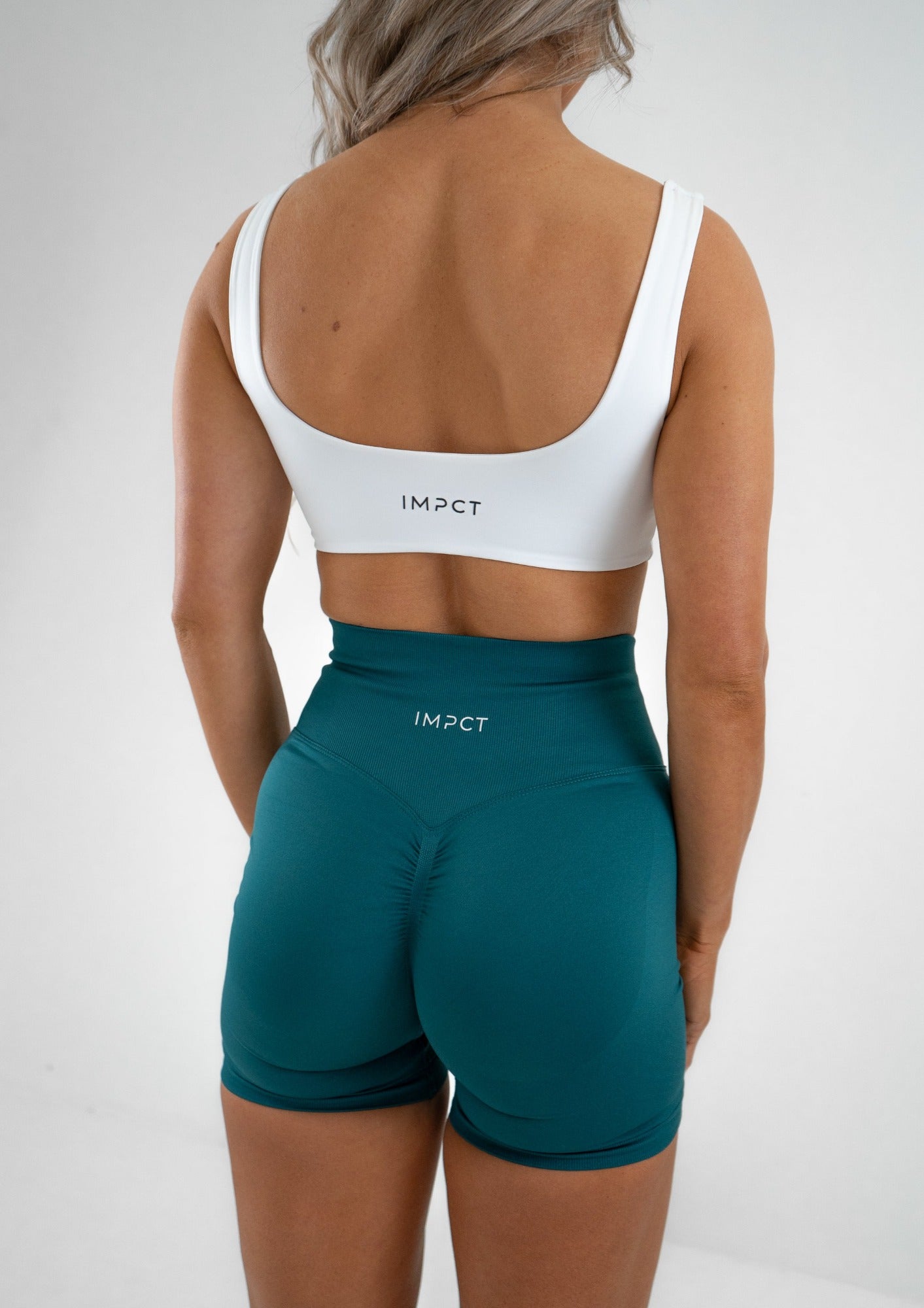 Model wearing a white activewear bra and green shorts set