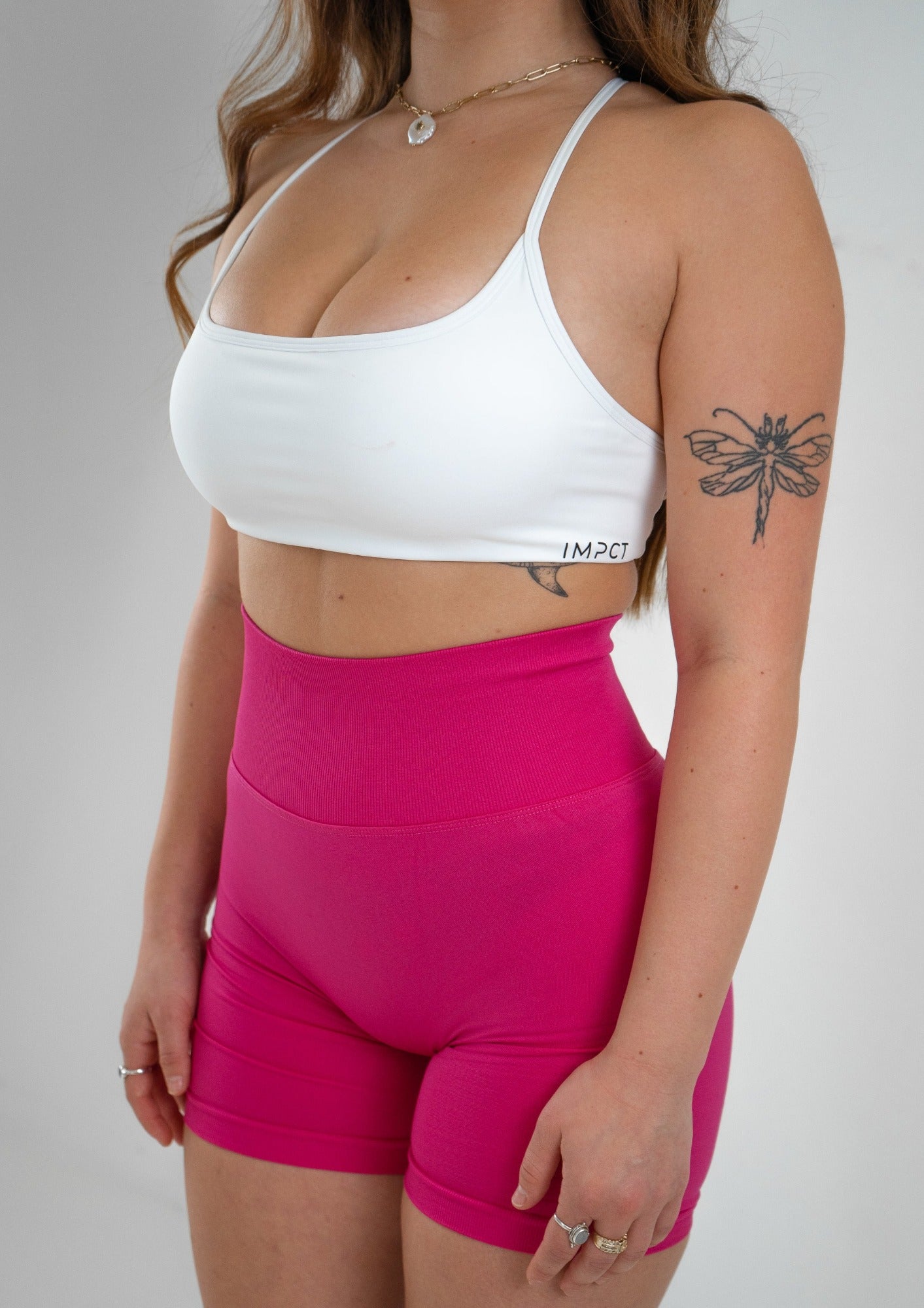 Model wearing a white activewear bra and hot pink shorts set