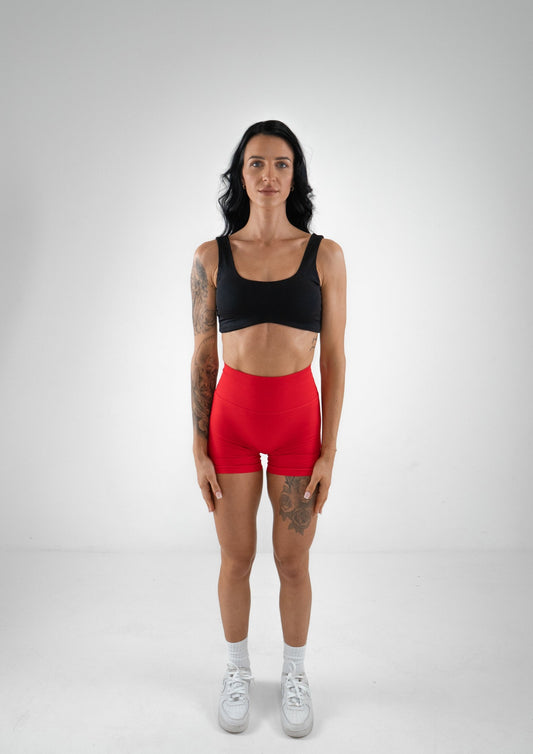 Model wearing a black activewear bra and red shorts set