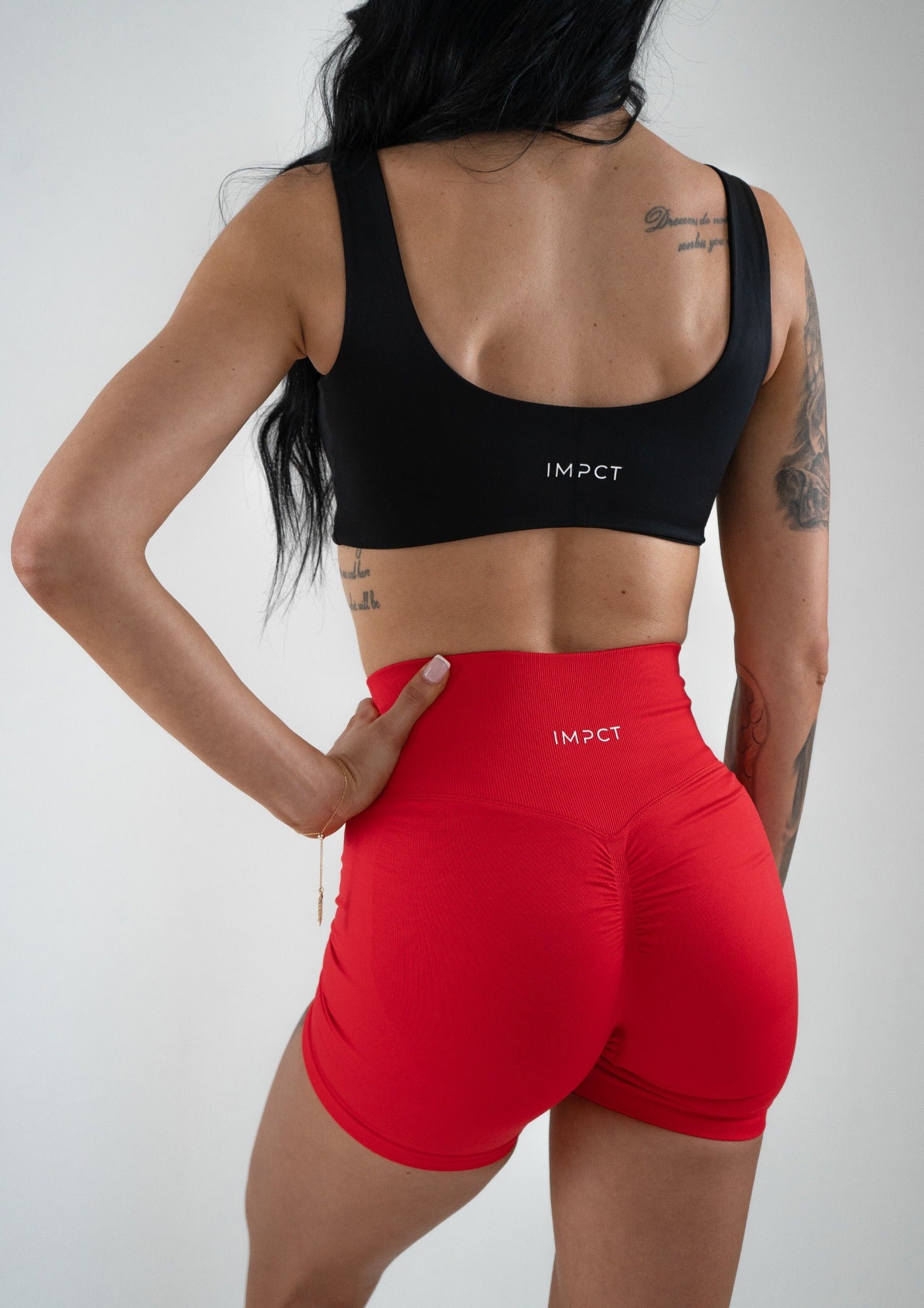 Model wearing a black activewear bra and red shorts set