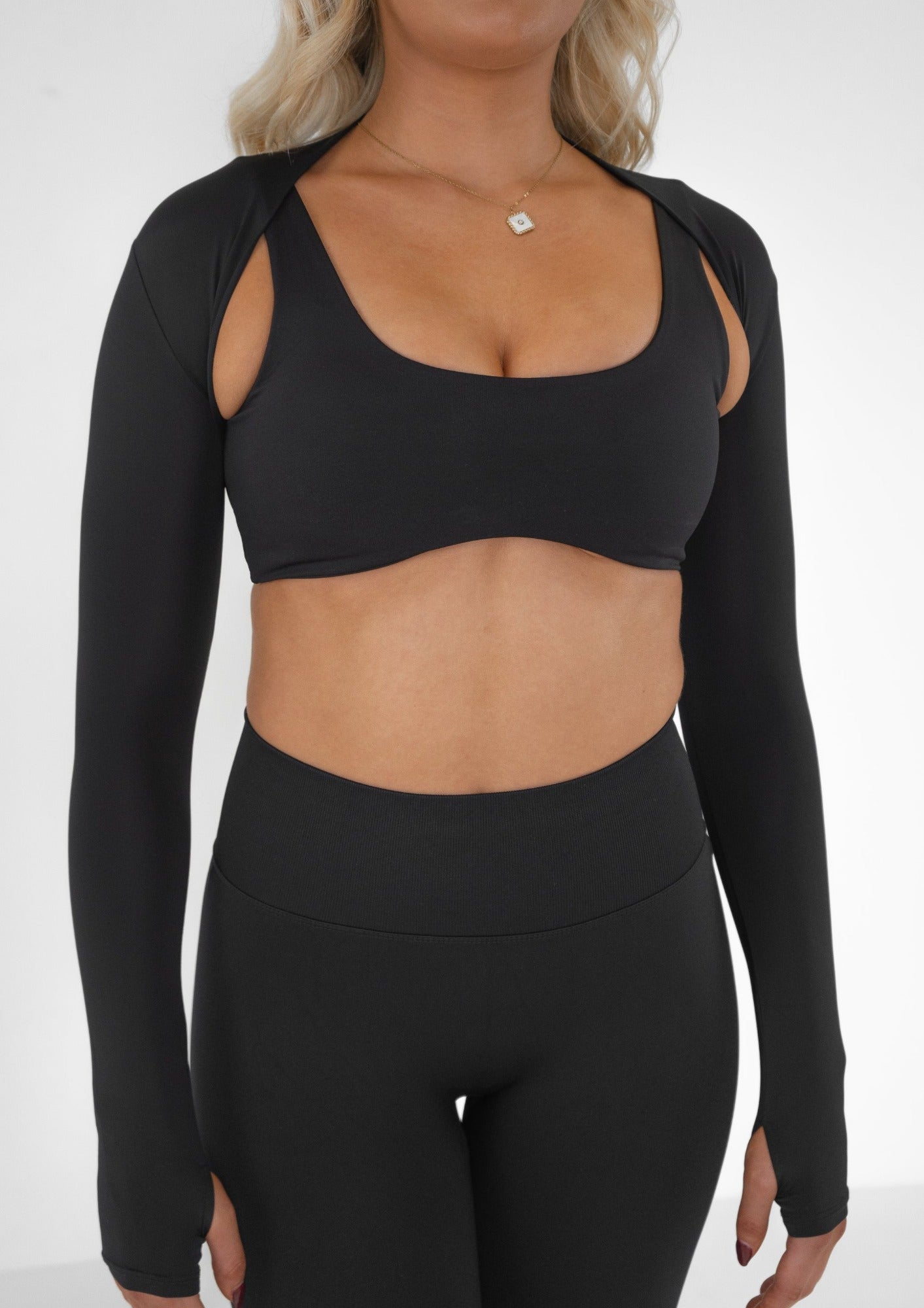 Model wearing a black activewear bra and leggings set with a black bolero